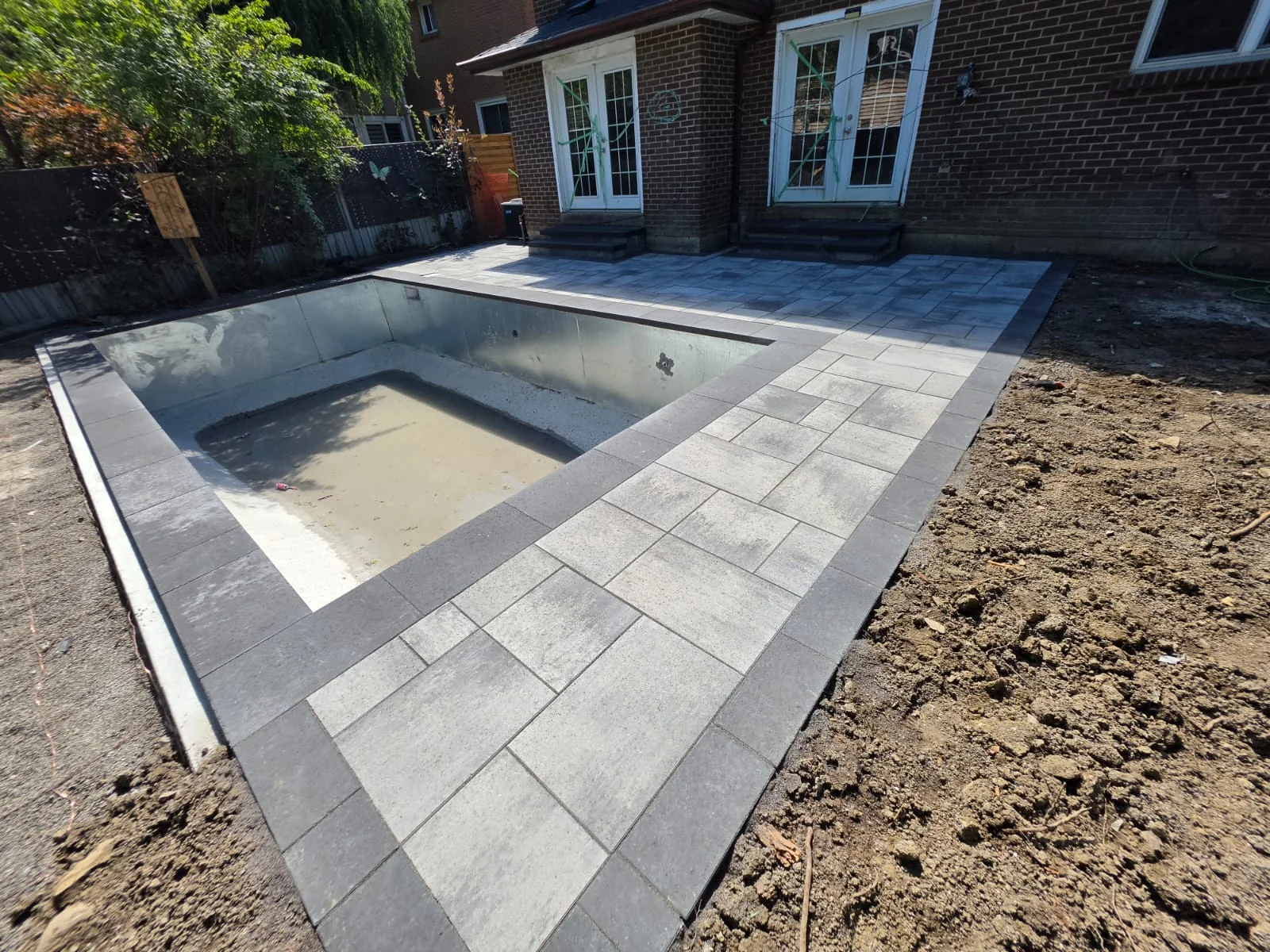 Pool shell with stone coping and surrounding paving