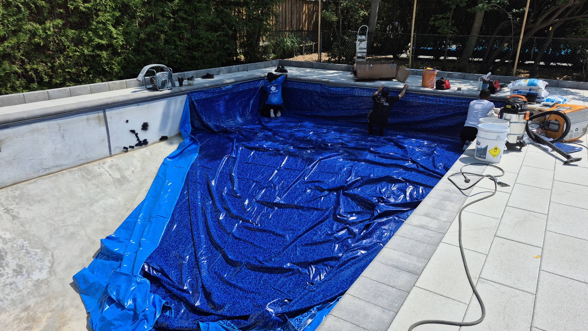 OPS crew fitting the blue liner along the walls of George’s pool